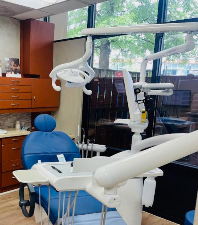 The image features a dental office interior with a modern dental chair, a dental examination table, and various dental equipment.