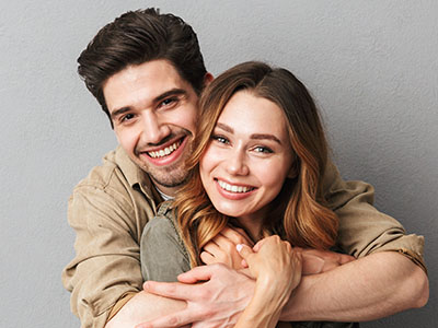 A young couple hugging each other closely, both smiling broadly.