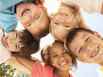 The image shows a group of children posing together with smiles on their faces, looking directly at the camera.