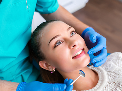 A woman receiving dental care with a hygienist performing the procedure.