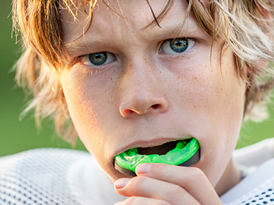 The image features two photos of a young boy with blonde hair, wearing a football uniform with a jersey number visible, holding a toothbrush in his mouth that has toothpaste on it.