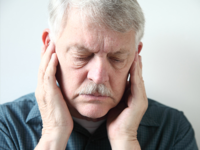 The image shows two side-by-side photographs of an older man with his hands on either side of his head, likely in a state of distress or discomfort.